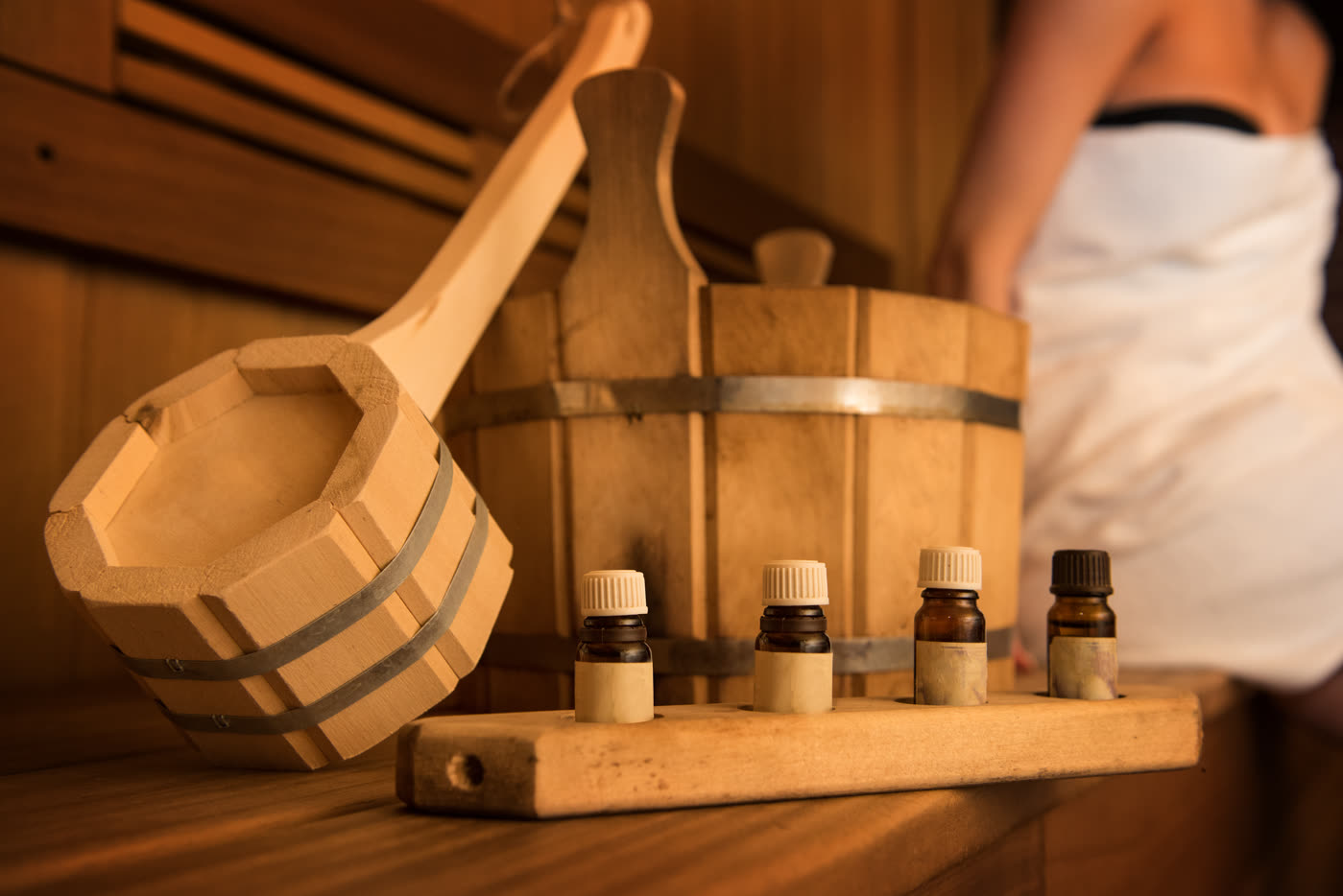 Sauna accessories with wooden bucket, towel, and oils.