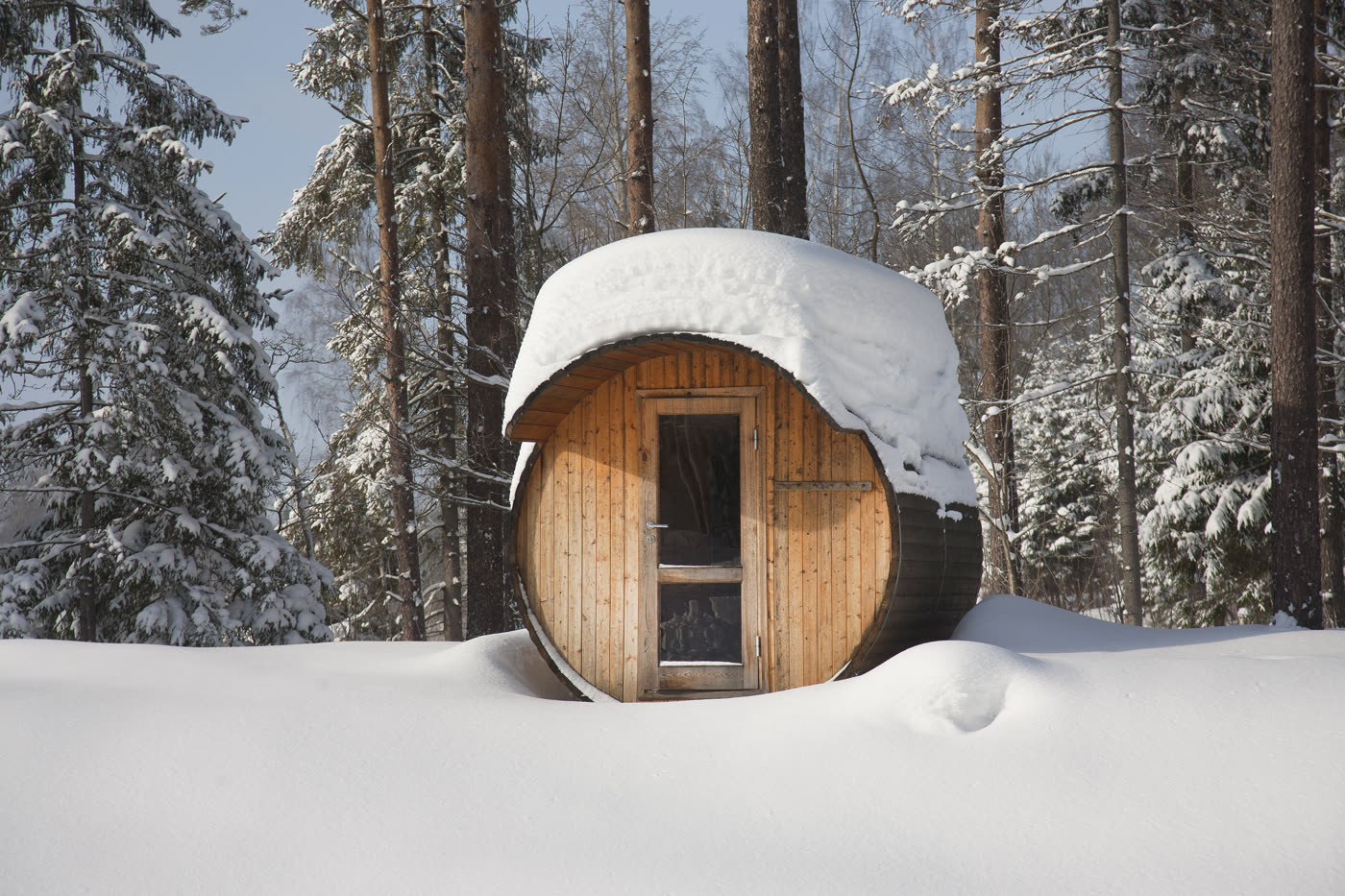 Outdoor barrel sauna in a backyard winter setting.